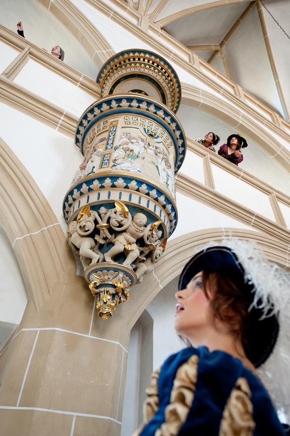 Innenansicht des Schlosses Hartenfels mit dekorativem Säulenornament wird von verkleideter Figur beobachtet